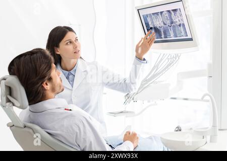 Jolie dentiste médecin démontrant son patient les résultats radiologiques Banque D'Images