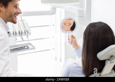 Femme Sattisfied clinique dentaire de client smiling at mirror Banque D'Images