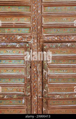 Volets en bois ornés rustiques complexes avec motifs floraux colorés arabesques marocains traditionnels peints à la main, beauté vieillie et altérée, texturée Banque D'Images