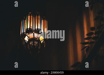 Traditionnel verre coloré marocain pendentif lumière Casting complexes ombres sur le plafond, chaleureuse atmosphère romantique accueillante dans un hébergement riad, m Banque D'Images