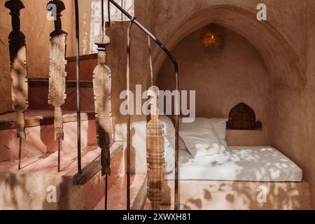 Un coin de sièges marocain minimaliste confortable dans un riad avec un escalier carrelé courbé. les murs sont texturés, rustiques terreux, avec un éclairage design doux a. Banque D'Images