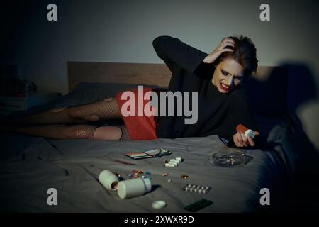 Une femme en jupe rouge et pull noir pose sur un lit dans une pièce faiblement éclairée. Banque D'Images