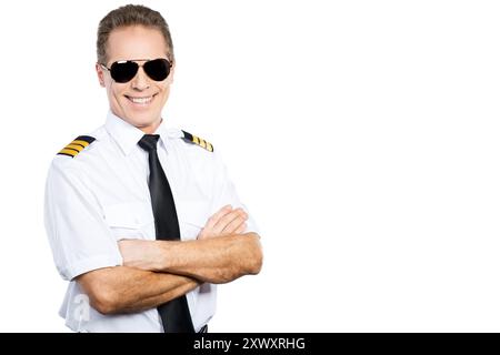 Pilote confiant. Pilote masculin confiant en uniforme gardant les bras croisés et souriant tout en se tenant debout sur fond blanc Banque D'Images