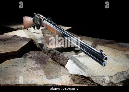 Fusil qui est longueur de carabine et action de levier sur les rochers avec un fond sombre. Banque D'Images