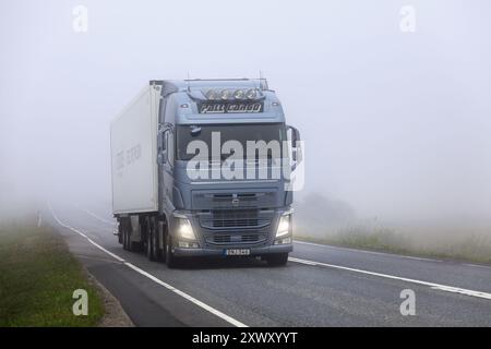 Semi-remorque de camion Volvo FH bleu clair émergeant du brouillard car il transporte des marchandises sur l'autoroute 9. Humppila, Finlande. 8 août 2024. Banque D'Images