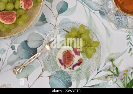 Dessert élégant - cupcake à la crème et à la figue, raisins verts sur une assiette en verre. Décoration vue de dessus. Banque D'Images