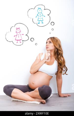 Garçon ou fille ? Femme enceinte réfléchie regardant vers le haut et tenant la main sur le menton tout en regardant sur fond blanc Banque D'Images