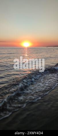 Le coucher de soleil se reflétant dans les vagues de la mer. Effet de décalage d'inclinaison. Banque D'Images