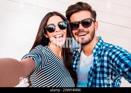 La Capture de moments lumineux. Jeune couple aimant faire joyeuse sur selfies caméra lors de standing outdoors Banque D'Images