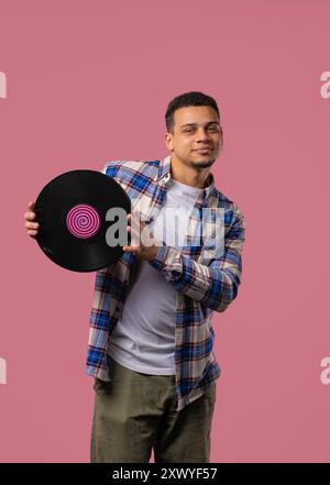 Homme dansant afro-américain élégant avec disque vinyle sur rose. Banque D'Images