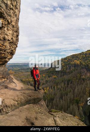 Photographe voyageur avec un sac à dos photo et trépied se tient sur un rocher. Parc national de la Suisse saxonne. Allemagne Banque D'Images