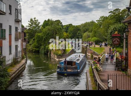 Un homme dirige un bateau de vacances à Newbury Lock sur le canal Kennet et Avon, Newbury, Berkshire, Angleterre, Royaume-Uni Banque D'Images