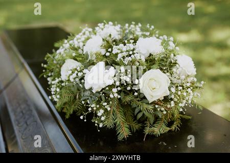 Grand bouquet rond composé de rose et arbre à fourrure sur cercueil en bois noir Banque D'Images