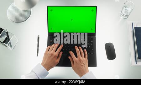 Travailleur de bureau anonyme tapant sur un ordinateur portable avec écran vert maquette Chromakey avec balises Motion Tracker. Manager correspondant avec les partenaires commerciaux par e-mail. Vue de haut en bas Banque D'Images