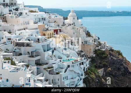 Santorin, Grèce - 8 octobre 2019 : vue emblématique des églises au dôme bleu et des maisons blanchies à la chaux perchées sur les falaises au-dessus de la mer Égée. Banque D'Images