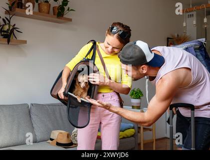 Jeune couple avec leur petit chien dans une maison de déménagement de porte-animaux ou de partir en voyage. Animaux de compagnie et propriétaires ensemble. Banque D'Images