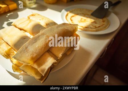 Gros plan de galettes dorées roulées maison avec du fromage blanc empilées sur une assiette sur le comptoir de la cuisine Banque D'Images
