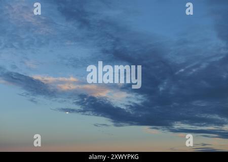 Des nuages colorés remplissent le ciel du soir au coucher du soleil. Banque D'Images