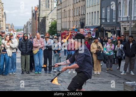 Edinburgh Festival Fringe, Royal Mile, Écosse, Royaume-Uni 21 août 2024. Troisième semaine mercredi sur le mile, un peu moins occupé et le public plus petit qu'auparavant. Temps très venteux avec des sorts ensoleillés et des averses. Photo : Rugg Tomcat jonglant avec des torches de feu sur le Royal Mile. Credit : Arch White/Alamy Live news. Banque D'Images