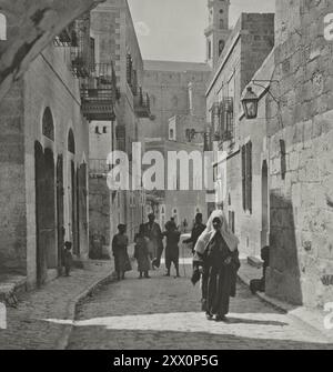 La vie en Palestine au début du XXe siècle. Rue à Bethelem avec église ou la Nativité ; montrant femme avec robe de tête typique. Palestine historique. 1919 Banque D'Images