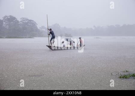 Feni, Chittagong, Bangladesh. 21 août 2024. 21 août 2024, Feni, Bangladesh : une famille tente de se mettre en sécurité par bateau pendant les fortes pluies dans la zone de Munsirhat du district de Feni de la division de Chittagong, Bangladesh. Mercredi 21 août, les eaux des rivières Muhuri, Kahua et Ceylan ont été vues couler au-dessus du niveau de danger de 86 cm, les routes et les maisons n'ont pas été épargnées par l'eau de la forêt. Plus de 200 000 personnes de trois upazilas ont été désorientées par la terrible catastrophe humanitaire. Dans cette situation, ces zones sont complètement sans électricité. (Crédit image : © Muhammad AM Banque D'Images