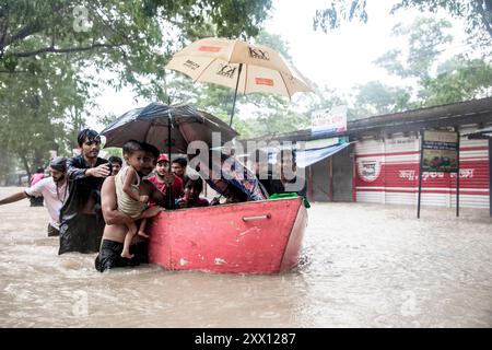 Feni, Chittagong, Bangladesh. 21 août 2024. 21 août 2024, Feni, Bangladesh : volontaires dans la zone de Munsirhat du district de Ã¢â‚¬''¹Ã¢â‚¬''¹Feni de la division de Chittagong au Bangladesh. Les femmes et les enfants pris au piège des inondations sont mis en sécurité par bateau. Mercredi 21 août, les eaux des rivières Muhuri, Kahua et Ceylan ont été vues couler au-dessus du niveau de danger de 86 cm, les routes et les maisons n'ont pas été épargnées par l'eau de la forêt. Plus de 200 000 personnes de trois upazilas ont été désorientées par la terrible catastrophe humanitaire. Dans cette situation, ces zones sont complètement sans électri Banque D'Images