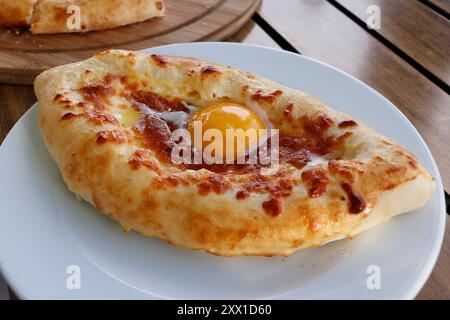 Pain géorgien traditionnel avec fromage, beurre, jaune d'œuf connu sous le nom d'adjaruli khachapuri en gros plan sur une table Banque D'Images