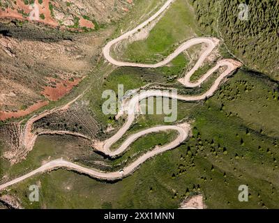 Vue aérienne d'une route de montagne sinueuse courbes, Kalmak Ashuu Pass, à travers une végétation luxuriante au Kirghizistan, Asie centrale, Asie Banque D'Images