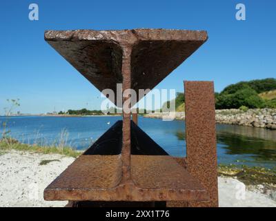 Poutre en acier rouillé avec un profil en double T, vestige d'une ancienne jetée, symbolise les reliques industrielles et la résistance portante des structures passées. Banque D'Images