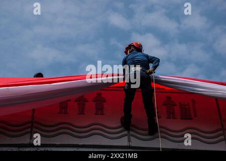 Bandung, Indonésie. 17 août 2024. Un pompier descend d'un pont pour hisser un drapeau rouge et blanc géant lors d'un salut de trois minutes commémorant le 79e jour de l'indépendance de la République d'Indonésie à Bandung, le 17 août 2024. (Photo de Dimas Rachmatsyah/Pacific Press/Sipa USA) crédit : Sipa USA/Alamy Live News Banque D'Images