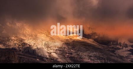 Lumière du soleil qui coule à travers les nuages de tempête atmosphériques avec la lumière du soleil sur les sommets des montagnes et un glacier, Suisse Banque D'Images