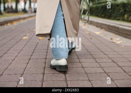 Vue arrière basse d'une femme dans un trench-coat marchant à travers le parc en automne, Biélorussie Banque D'Images
