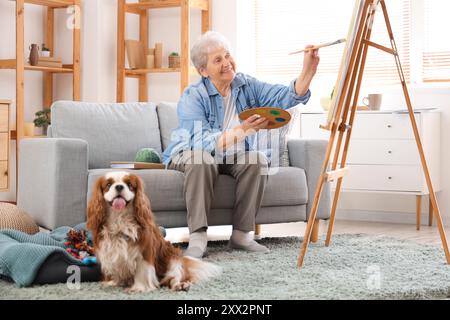 Femme senior avec la peinture de chien cavalier roi Charles spaniel mignon à la maison Banque D'Images