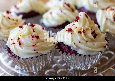 Vue rapprochée de cupcakes en velours rouge sur une plaque de verre transparente sur une table en bois. Banque D'Images