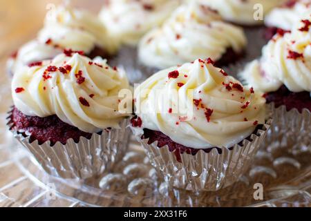 Vue rapprochée de cupcakes en velours rouge sur une plaque de verre transparente sur une table en bois. Banque D'Images
