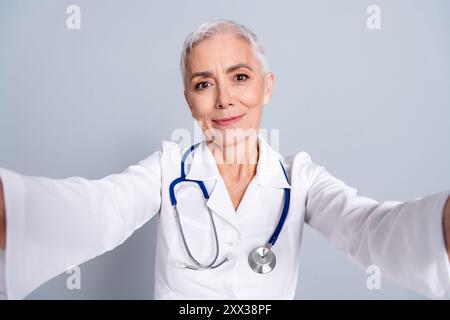 Photo de charmant médecin spécialiste qualifié femme enregistrer la vidéo prendre selfie isolé sur fond de couleur grise Banque D'Images