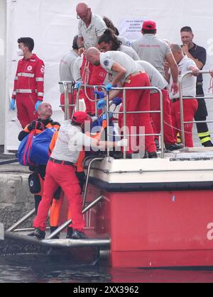 Le cinquième sac corporel est ramené à terre au port de Porticello par des sauveteurs à la recherche des six touristes disparus après que le yacht de luxe Bayesian a coulé dans une tempête lundi alors qu'il était amarré à environ 800 mètres au large de la côte sicilienne. Date de la photo : jeudi 22 août 2024. Banque D'Images