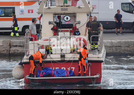 Le cinquième sac corporel est ramené à terre au port de Porticello par des sauveteurs à la recherche des six touristes disparus après que le yacht de luxe Bayesian a coulé dans une tempête lundi alors qu'il était amarré à environ 800 mètres au large de la côte sicilienne. Date de la photo : jeudi 22 août 2024. Banque D'Images