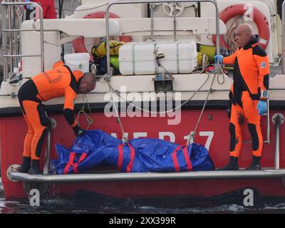 Le cinquième sac corporel est ramené à terre au port de Porticello par des sauveteurs à la recherche des six touristes disparus après que le yacht de luxe Bayesian a coulé dans une tempête lundi alors qu'il était amarré à environ 800 mètres au large de la côte sicilienne. Date de la photo : jeudi 22 août 2024. Banque D'Images