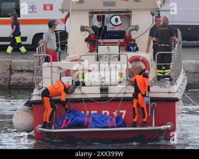 Le cinquième sac corporel est ramené à terre au port de Porticello par des sauveteurs à la recherche des six touristes disparus après que le yacht de luxe Bayesian a coulé dans une tempête lundi alors qu'il était amarré à environ 800 mètres au large de la côte sicilienne. Date de la photo : jeudi 22 août 2024. Banque D'Images