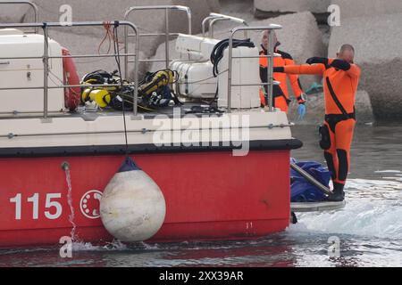 Le cinquième sac corporel est ramené à terre au port de Porticello par des sauveteurs à la recherche des six touristes disparus après que le yacht de luxe Bayesian a coulé dans une tempête lundi alors qu'il était amarré à environ 800 mètres au large de la côte sicilienne. Date de la photo : jeudi 22 août 2024. Banque D'Images