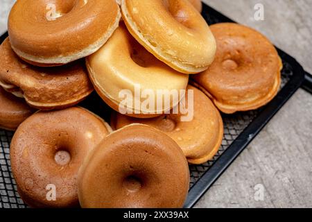 Une pile de mini beignets sur un plateau noir. Les mini beignets sont tous de tailles et de formes différentes Banque D'Images