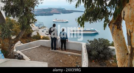 Santorin, Grèce - 8 octobre 2019 : couple regarde les bateaux de croisière dans la caldeira. Banque D'Images