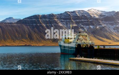 Un grand bateau est amarré à un quai à côté d'un plan d'eau. La scène est sereine et paisible, avec le bateau et l'eau créant un sentiment de calme Banque D'Images