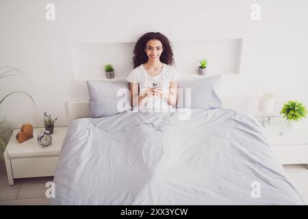 Photo de charmante jeune femme couchée dispositif de retenue de lit bon matin vibes éveillé maison chambre lumière intérieur blanc Banque D'Images