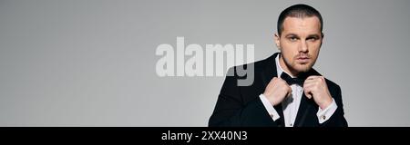 Un homme dans un smoking ajuste son noeud papillon avec une expression concentrée. Banque D'Images