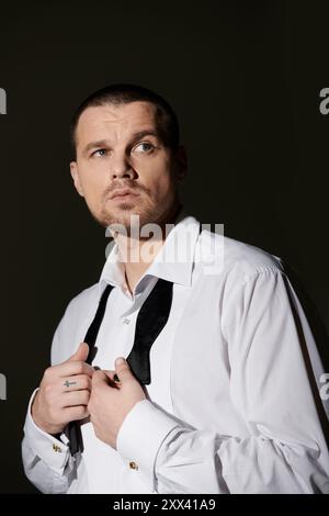 Un homme ajuste son noeud papillon, exsudant confiance et style. Banque D'Images