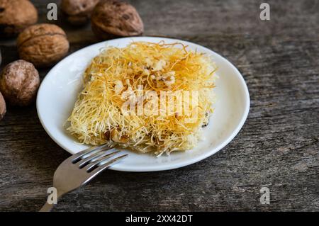 Dessert turc fait maison kadayif sur assiette avec des noix, pâte râpée cuite au sirop recouverte de noix écrasées, délice turc Banque D'Images