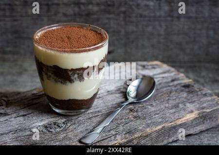 Tiramisu, dessert italien traditionnel en verre sur fond de bois. Mise au point sélective Banque D'Images