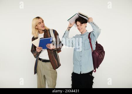 Deux jeunes étudiants, vêtus de façon décontractée, se tiennent sur un fond gris, montrant leur amitié et embrassant leur identité. Banque D'Images